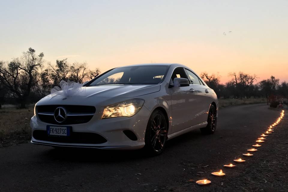 La Mercedes CLA al tramonto, con un fiocco di tulle sul cofano e una fila di lumini accanto